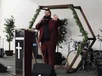 a man in a red suit standing at a podium