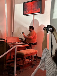 a woman taking a picture of a man playing a piano