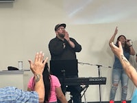 a group of people with their hands raised in front of a microphone