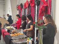 a group of people standing around a table with food