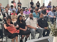 a group of people sitting in chairs and listening to a speaker