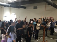 a group of people standing in a room with their hands raised