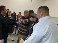 a man is hugging a man in front of a group of people