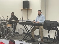 a man playing a keyboard in front of a group of people