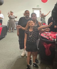 a group of people standing in a room with red and black balloons