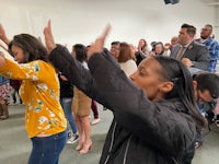 a group of people raising their hands in a room