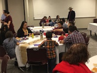 a group of people eating at a table in a classroom