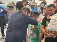a group of people standing around a man holding a child