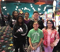 a group of kids posing in front of a video game machine