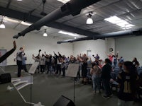 a group of people in a room raising their hands
