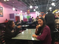two girls sitting at a table eating ice cream