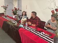 a group of people sitting at a table with a red and black tablecloth