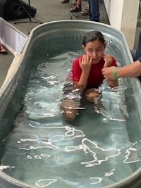 a young girl is being baptized in a tub