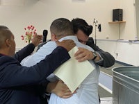 two men hugging each other in front of a microphone
