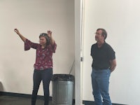 two people standing next to each other in an office