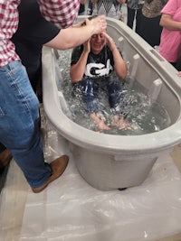 a person being baptized in a tub of water