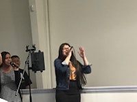 a woman singing in front of a group of people