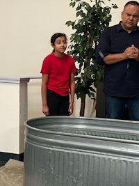 a man and a child standing next to a metal tub