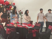a group of people standing around a table with balloons