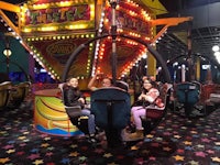 three people sitting on a carousel in an amusement park