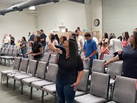 a group of people standing in a room full of chairs
