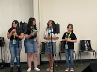 a group of girls standing in front of microphones