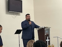a man in a suit speaking into a microphone