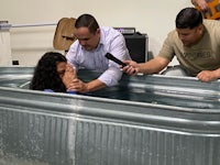 a woman is being baptized in a metal tub