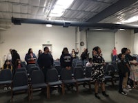 a group of people standing in a room with chairs