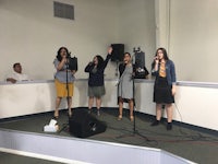 a group of people singing in front of microphones