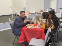 a group of people eating at a table in a room