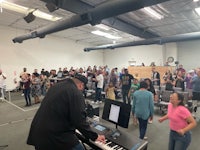 a group of people standing in a room with a piano