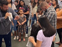 a group of people standing in front of a group of children