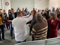 a group of people standing in a room with their hands raised
