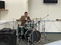 a man playing drums in a room with a tv