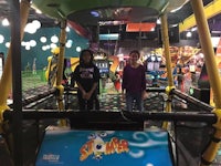 two girls standing in front of a ride at an indoor amusement park