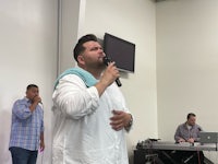 a man in a white shirt singing into a microphone