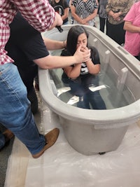 a woman is being baptized in a bathtub