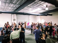 a group of people in a room raising their hands