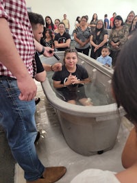 a group of people standing around a tub of water