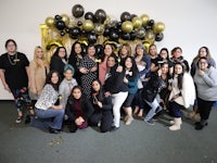 a group of women posing for a photo in front of balloons