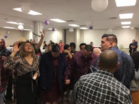 a group of people standing in a room with balloons