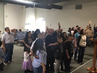 a group of people standing in a room with their hands raised