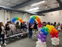 a group of people standing in a room with balloons