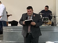 a man in a suit is reading a book in a church