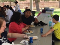 a group of people eating at a picnic table