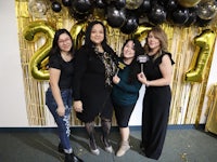 four women posing for a photo in front of balloons