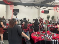 a group of people at a table with red and black decorations
